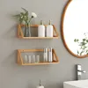 Two wooden shelves mounted on a gray wall, holding bathroom accessories and decorative items. Produktbild-Vorschau