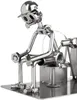 A metal figurine of a person sitting on a stool, made from nuts and bolts. Produktbild-Vorschau