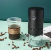 A coffee grinder and a glass of coffee sit on a table, surrounded by coffee beans. Produktbild-Vorschau