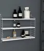 A white modular wall shelf with various bathroom products displayed on it. Voir les images du produit