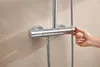 A hand is adjusting a chrome shower mixer on a tiled wall. Anteprima dell’immagine prodotto