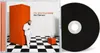 A CD case and CD are displayed next to each other. The CD case shows a man in a white suit standing next to an orange structure on a black and white checkered floor. Produktbild-Vorschau