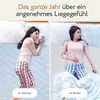 A split image showing a woman sleeping on a mattress in summer and winter settings, highlighting the product's year-round comfort. Produktbild-Vorschau