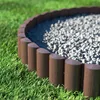 A close-up view of a garden border made of brown plastic logs with a wood texture, separating a patch of green grass from a bed of small gray stones. Náhľad obrázku produktu