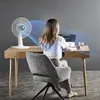 A woman is working on a laptop at a desk, with a fan blowing air towards her. Náhľad obrázku produktu