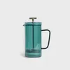 A green glass French press coffee and tea maker with a gold handle on a white background. Produktbild-Vorschau