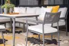 An outdoor dining set with a table and chairs on a patio with a patterned rug. Produktbild-Vorschau