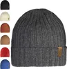 Multiple colors of knitted beanies are displayed in a collage with a large dark gray beanie in the foreground. Produktbild-Vorschau