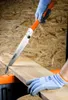 A person wearing gloves is using a folding Japanese saw to cut a wooden plank. Produktbild-Vorschau