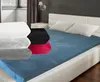 A bed with multiple stacked fitted sheets in different colors, and one fitted sheet spread out on the bed. Produktbild-Vorschau