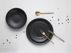 A set of black plates and gold cutlery arranged on a white background with scattered confetti. Náhľad obrázku produktu