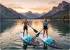 A man and a woman paddleboarding on a lake with mountains in the background during sunset. Náhled obrázku produktu