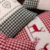 Close-up view of several decorative pillows with checkered patterns and embroidered designs. Produktbild-Vorschau