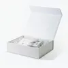 An open white gift box with shredded white paper filling, containing a necklace and a small silver gift box with a ribbon. Produktbild-Vorschau