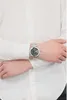 A person wearing a white shirt and a silver watch on their left wrist. Náhľad obrázku produktu