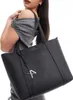 A woman is modeling a black tote bag. Podgląd zdjęcia produktu