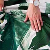 A person's hand is shown touching a duvet cover with a tropical leaf pattern. Podgląd zdjęcia produktu