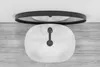 A top-down view of a white oval sink with a black faucet, placed on a wooden surface, with a black-rimmed mirror reflected above it. Podgląd zdjęcia produktu