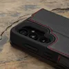 A close-up view of a black leather phone case with red stitching, showing the camera cutout. Anteprima dell’immagine prodotto