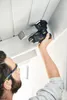 A person is using a cordless sander to sand a ceiling. Voir les images du produit