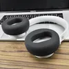 A pair of white and black headphones are placed on top of a laptop, which is on a wooden surface. Náhľad obrázku produktu