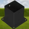 A black metal post anchor is shown in a garden setting with a blurred background of grass and sky. Náhled obrázku produktu