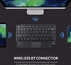A black Bluetooth keyboard with a touchpad is shown connected wirelessly to a tablet and a smartphone, with a computer monitor in the background. Text describes the wireless connection. Náhled obrázku produktu