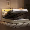 A white upholstered bed with its storage compartment open, revealing stored items. The bed has a headboard with integrated LED lighting and a digital clock. Produktbild-Vorschau