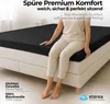 A person sitting on a black fitted sheet on a bed. Produktbild-Vorschau