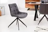 A gray upholstered dining chair with a black metal base is shown in a room with a wooden dining table and a rug. Produktbild-Vorschau