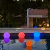 Colorful illuminated balls float in a swimming pool at dusk, with a modern house and trees in the background. Voir les images du produit