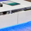 Close-up view of a modern white coffee table with open drawers, showing books and a tablet. Produktbild-Vorschau