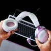 A person is holding a white and purple gaming headset in front of a black keyboard. Anteprima dell’immagine prodotto