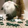 A Christmas-themed arrangement with a gnome, a glittery tree, and decorative stars on a patterned surface. Produktbild-Vorschau