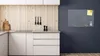 A modern kitchen with white cabinets and a wooden backsplash, featuring a magnetic board on the dark blue wall. Anteprima dell’immagine prodotto