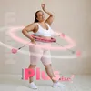 A woman is using a pink hula hoop with weights. Podgląd zdjęcia produktu