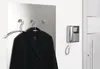 A coat hanging on a hanger on a wall panel, with an intercom system mounted on the adjacent wall. Podgląd zdjęcia produktu