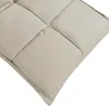 A close-up view of a beige upholstered floor chair cushion, showing its quilted texture and stitching. Voir les images du produit