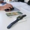 A desk with a person's hands using a computer mouse and keyboard, with a smartphone and smartwatch charging wirelessly. Produktbild-Vorschau