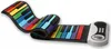 A flexible, rainbow-colored piano keyboard is laid out on a white background. The keyboard is partially unrolled, showing its colorful keys and a white control panel at one end. Produktbild-Vorschau
