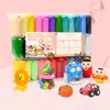 A collection of colorful modeling clay sticks and various clay creations, including a lion, a cupcake, a pumpkin, a car, a robot, and two figures, are displayed against a pink background. Náhled obrázku produktu