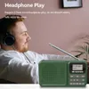 A man wearing headphones is listening to a green DAB radio. Produktbild-Vorschau