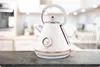 A white electric kettle with rose gold accents and a thermometer sits on a countertop in a blurred kitchen setting. Produktbild-Vorschau