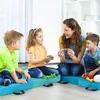A teacher or caregiver interacting with children, playing with colorful building blocks on blue floor cushions. Produktbild-Vorschau