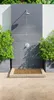 An outdoor shower area with a bamboo mat in front of a tiled shower wall. Produktbild-Vorschau