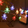 A string of colorful snowflake-shaped LED lights is draped across a dark background, suggesting a festive or decorative setting. Produktbild-Vorschau