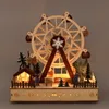 A wooden Ferris wheel decoration with LED lights, set in a winter scene with trees and figures. Náhled obrázku produktu