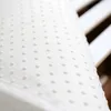 A close-up, angled view of a white mattress protector with a pattern of small raised dots. Produktbild-Vorschau