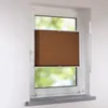 A brown pleated blind is installed on a white window frame, partially covering the view of green foliage outside. Produktbild-Vorschau