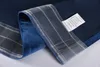 A close-up view of a folded blue velvet curtain with a plaid trim and a care label attached. Produktbild-Vorschau